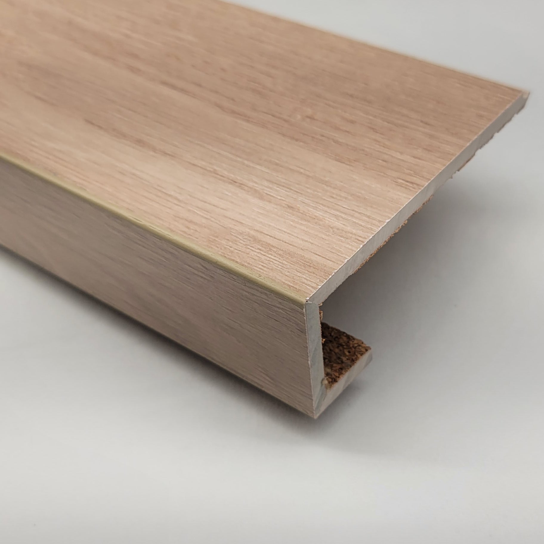 Close-up image of a laminate stair nosing with finished corners, built from laminate plank and detailed with color-matched epoxy for a seamless, professional look.