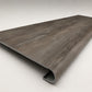 Custom round-nose stair tread made from DuraLux Performance Stormy Elm flooring. Round profile. Angled view.