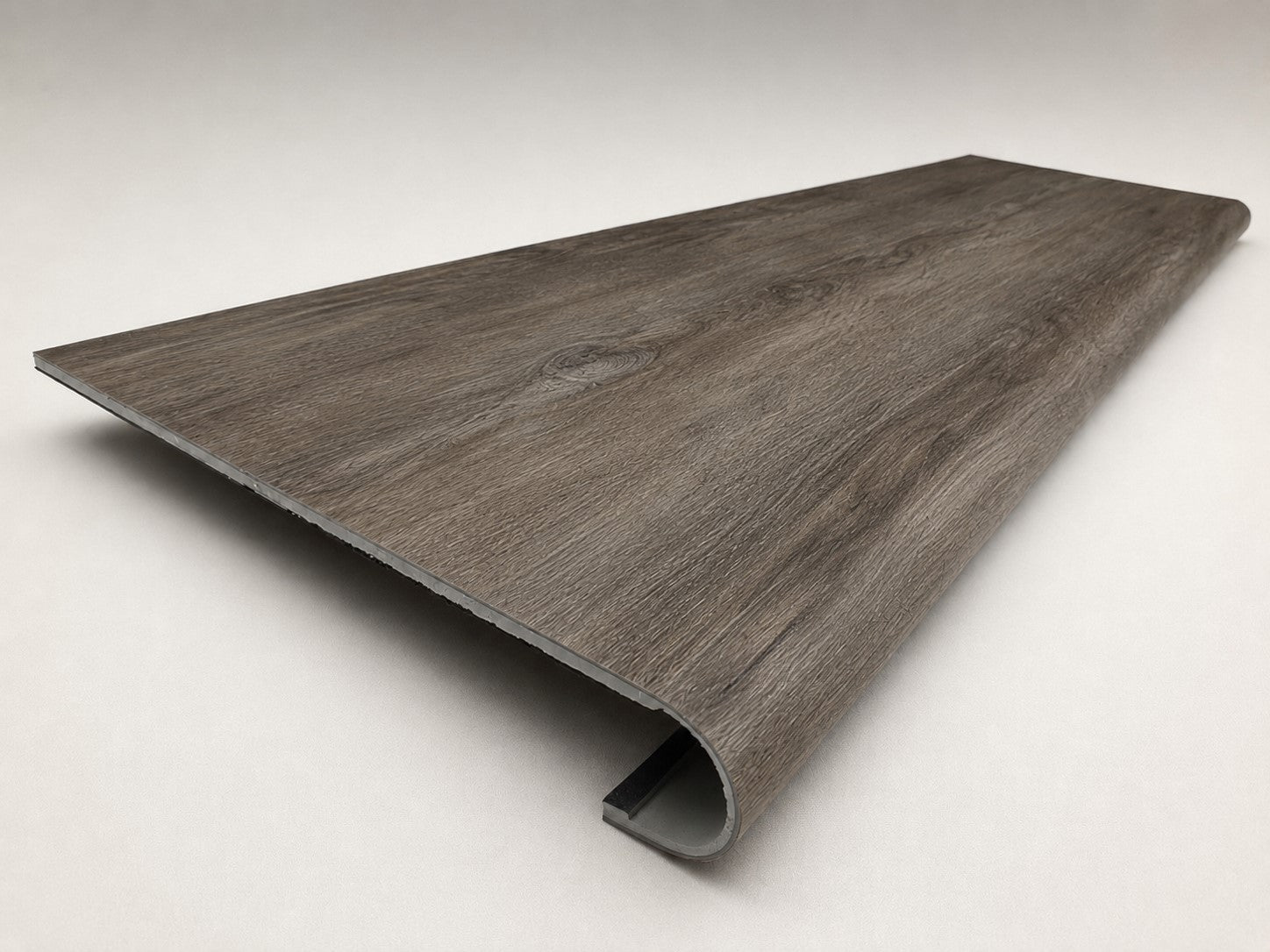 Custom round-nose stair tread made from DuraLux Performance Stormy Elm flooring. Round profile. Angled view.