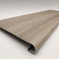 Custom round-nose stair tread made from DuraLux Performance Timber Saddle flooring. Round profile. Angled view.