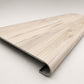 Custom round-nose stair tread made from LifeProof Navarra Maple Oak flooring. Round profile. Angled view.