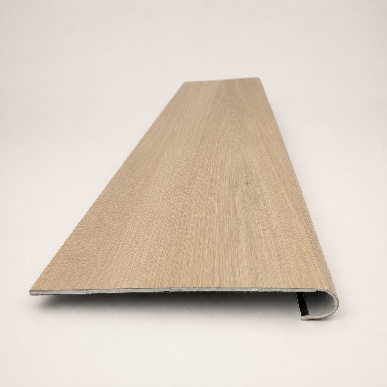 Custom round -nose stair tread made to match NuCore Caracal Crossing flooring. round profile. Front view.