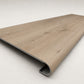 Custom round-nose stair tread made to match NuCore Deerfield Grove flooring. Round profile. Angled view.