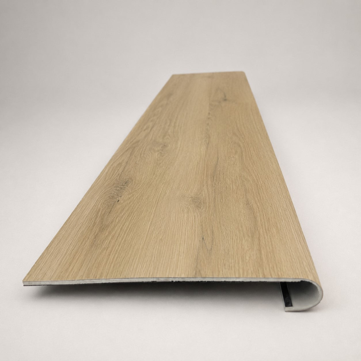 Custom round-nose stair tread made to match NuCore Fairborn Blonde flooring. Round profile. Front view.