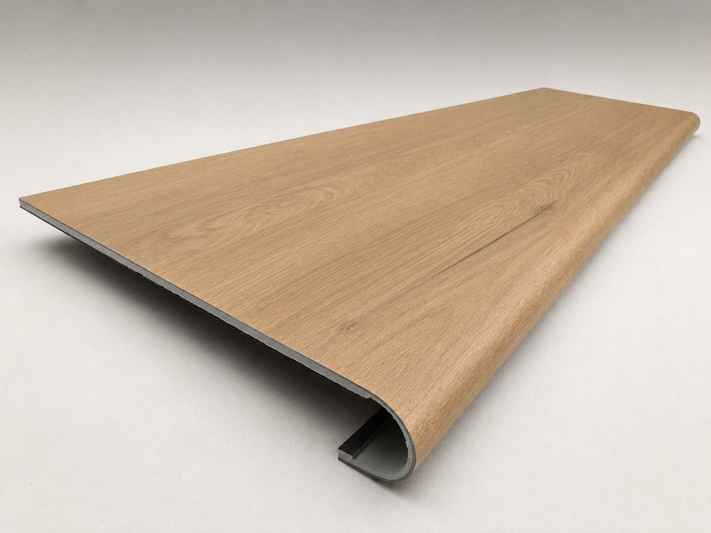 Custom round-nose stair tread made from NuCore Glenridge Oak flooring. Round profile. Angled view.