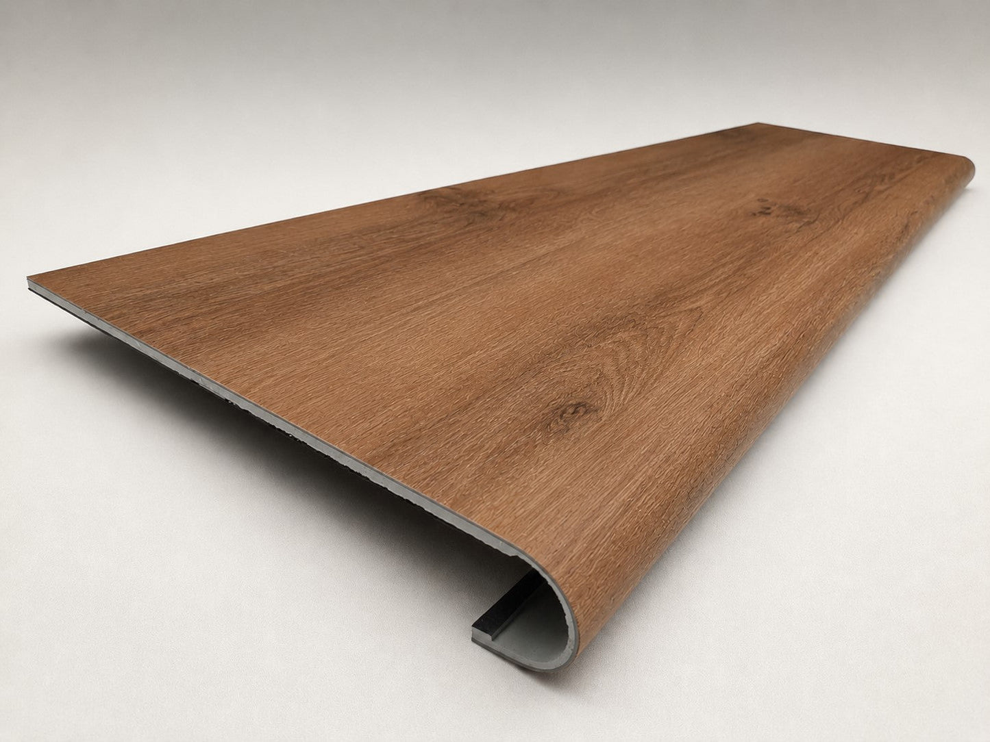 Custom round-nose stair tread made from NuCore Gunstock Oak flooring. Round profile. Angled view.