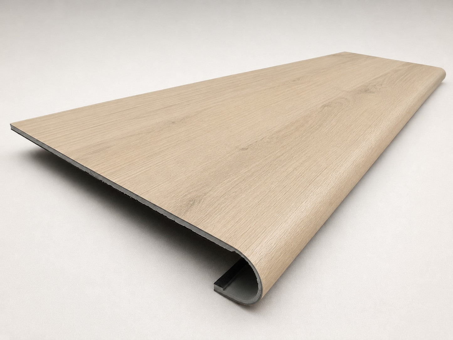 Custom round nose stair tread made from NuCore Nordic Oak flooring, showing a finished matching tread with light wood grain, smooth rounded profile, and professional product detail. Angled view