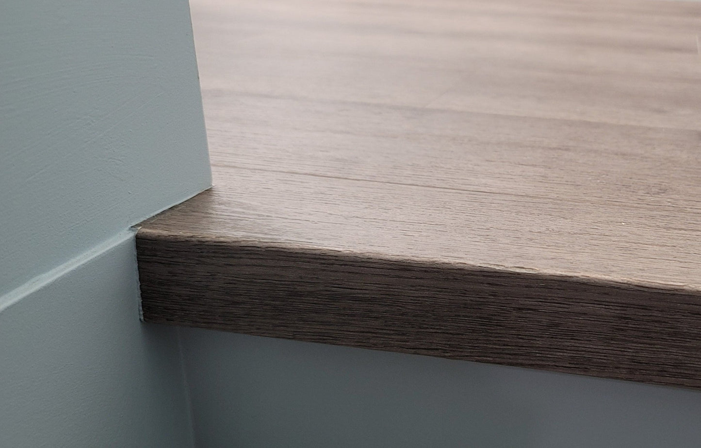 Close-up of flush vinyl stair nosing with square profile at top of stairs transitioning to landing, made from the exact Mohawk Home Torrey Oak vinyl plank